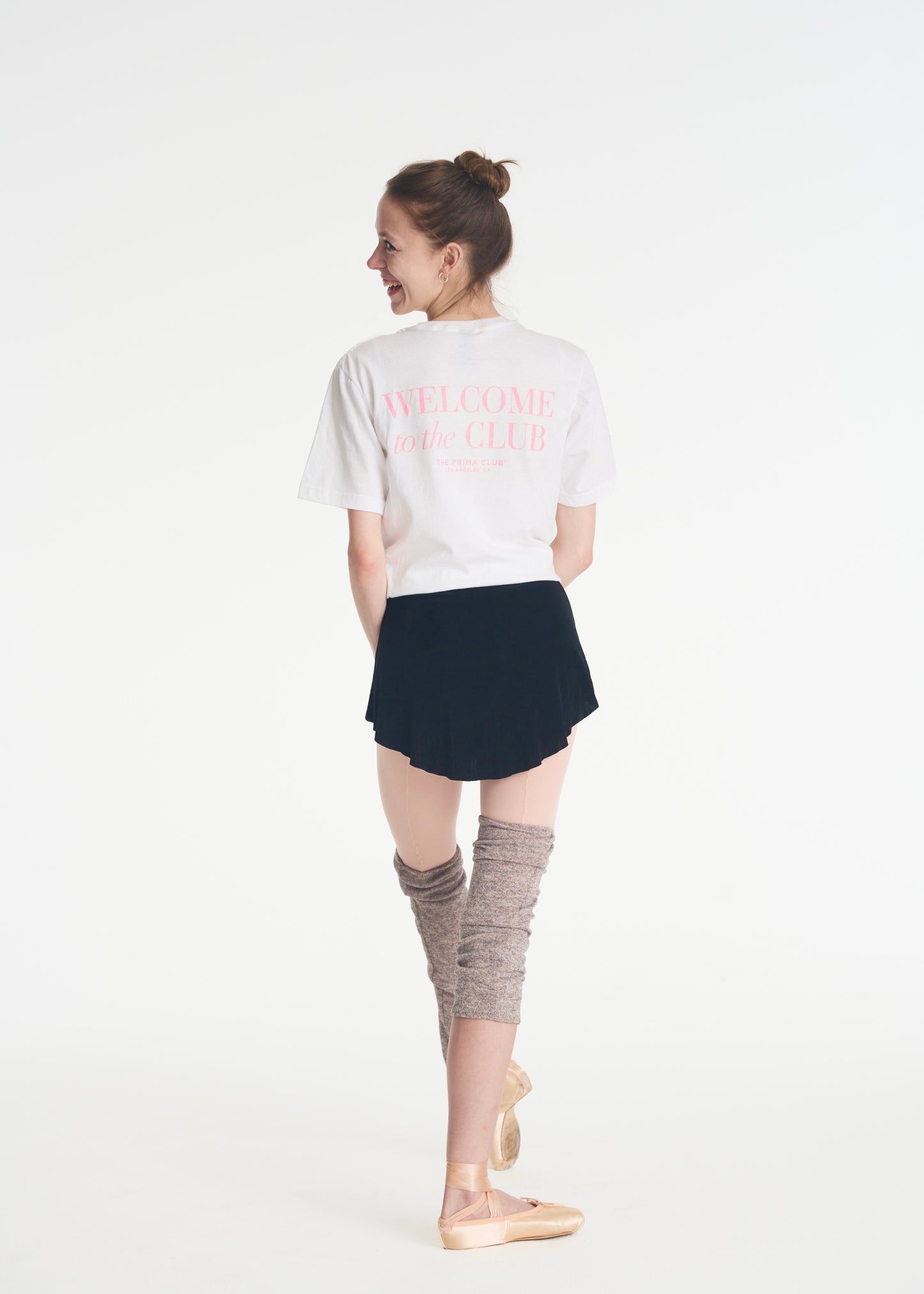 model facing backwards, looking over shoulder wearing welcome to the club t-shirt