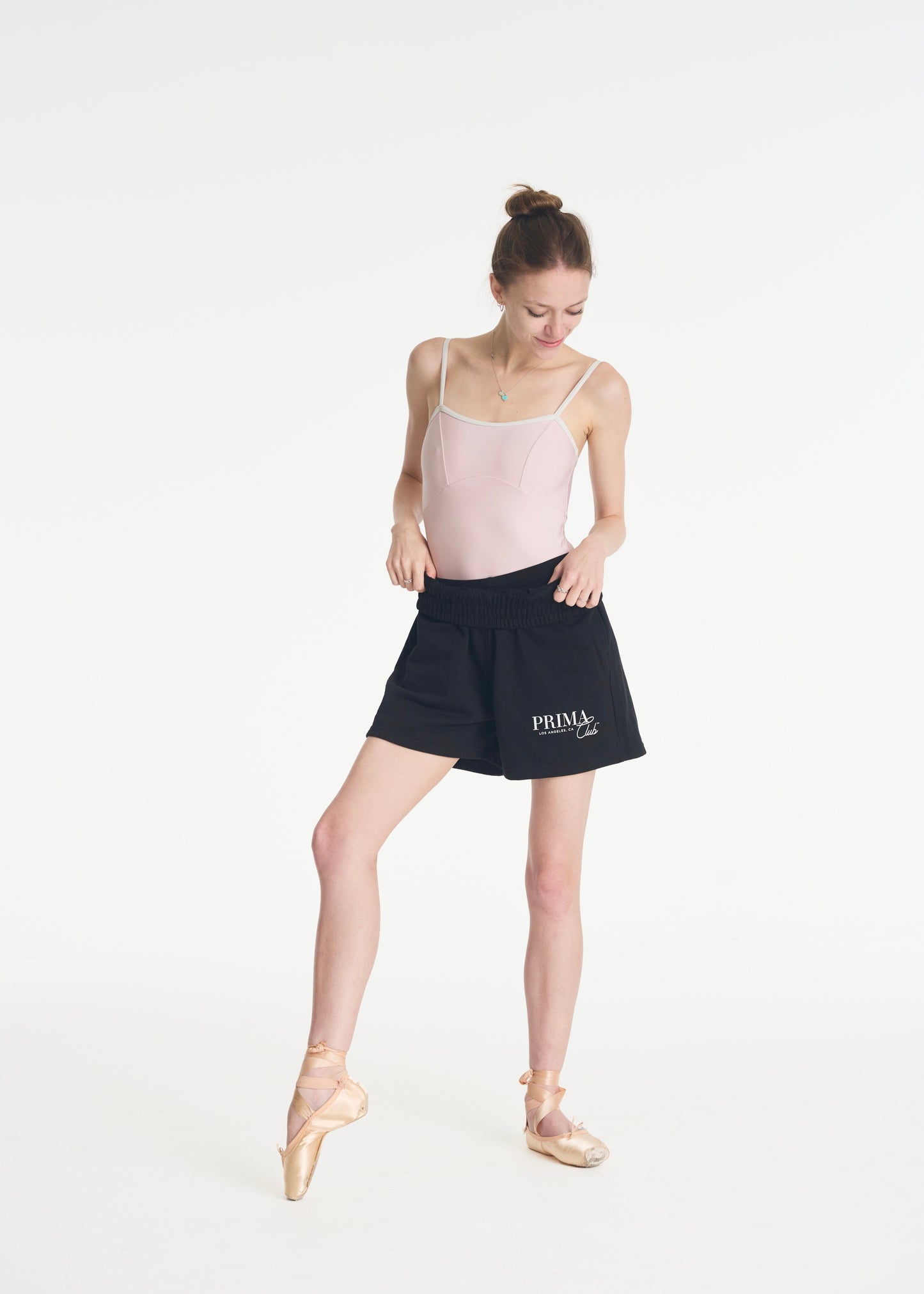 model looking down wearing black The Prima Club shorts
