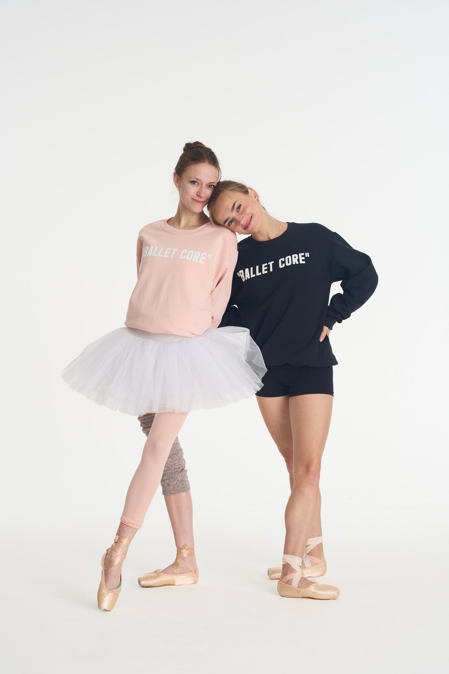 2 models leaning on eachother wearing pink and black ballet core crewnecks.